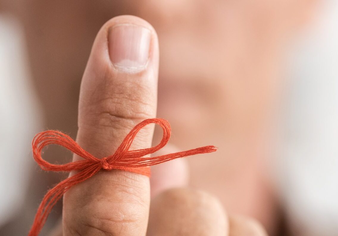 panoramic shot of red bow on finger of senior man with mental illness